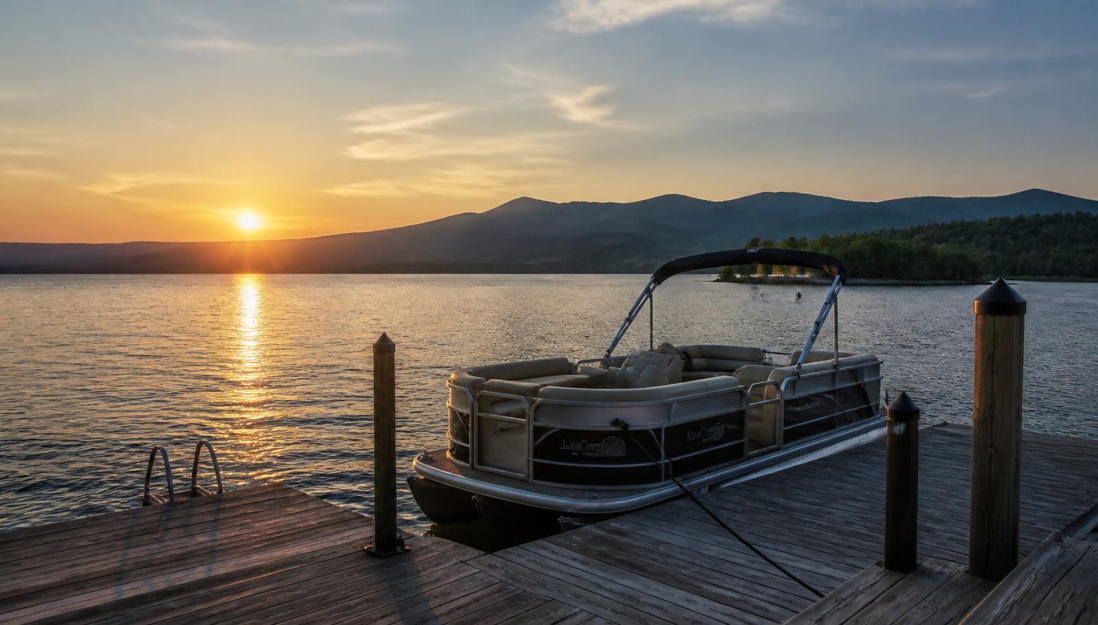 Dock with a pontoon boat on a calm lake at sunset — illustrative Douglas Lake scene.